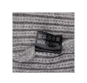 Close-up of the grey knitted beanie fabric with wash care label and origin mark