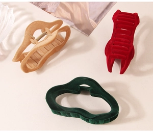 Dettaglio dei fermagli per capelli in velluto kaki, rosso e verde scuro dal design a onda