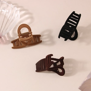 Three large flocked hair claws in black, coffee, and khaki shown on a cream background