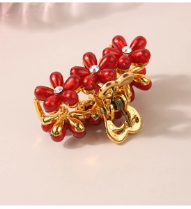 Dettaglio macro di molletta per capelli a fiore rosso con strass su base dorata