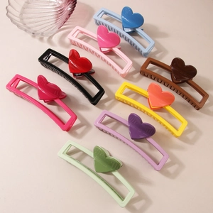 Set of nine colorful heart hair claws in a neat diagonal layout on a beige surface