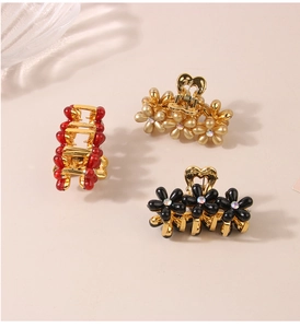 Vista macro dettagliata di tre mollette per capelli a fiore con strass in rosso, oro e nero
