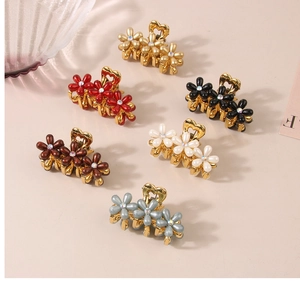 Dettaglio di sei piccole mollette per capelli a fiore con strass in vari colori