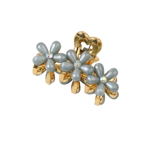 Dettaglio della pinza per capelli dorata con fiori blu grigi, strass e impugnatura a cuore