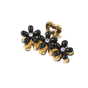 Dettaglio del fermaglio per capelli in metallo dorato con fiori neri e strass luccicanti