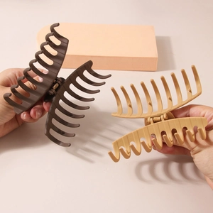 Pinces à cheveux géométriques mates élégantes en marron et kaki tenues dans les mains