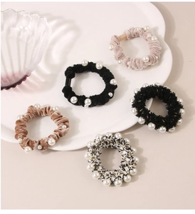 Detailed shot of velvet and tweed hair scrunchies with elegant white faux pearl accents