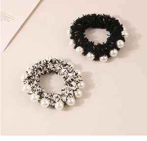 Close-up of velvet hair scrunchies with white faux pearls in black and white tweed style