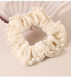 Dettaglio dell'elastico in velluto beige con perle bianche e piccoli strass luminosi