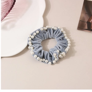 Dettaglio dell'elastico in velluto blu con perle bianche e una trama elegante e morbida
