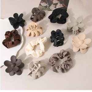 Detail view of earth-tone hair accessory set featuring floral clips and silk scrunchies