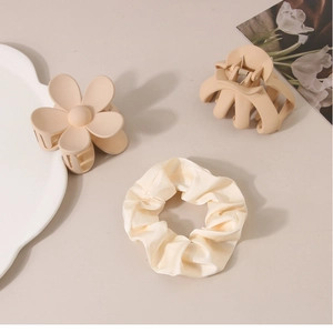 Detail of cream fabric scrunchie and matte beige floral hair claw clips set