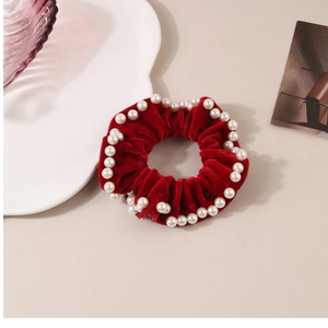 Dettaglio dell'elastico in velluto rosso con perline bianche e trama plissettata