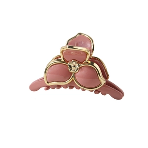 Détail d'une pince à cheveux rose en forme de fleur avec des bords dorés élégants