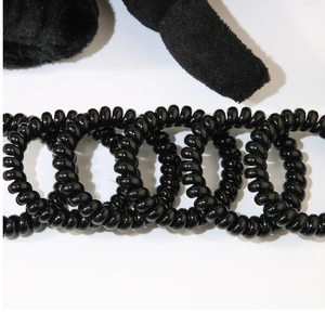 Detail of black spiral hair ties and plush accessories on a clean white background