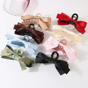 Elegant large satin bow hair claws in eight colors displayed on a minimalist background