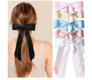 Détail de la pince à cheveux avec nœud en satin et longs rubans en noir, rose et beige