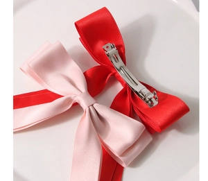 Vue détaillée des barrettes à nœuds en satin rouge et rose avec clips à ressort en métal