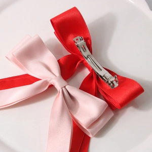 Élégantes barrettes nœuds en satin rouge et rose avec clips métalliques sur fond blanc