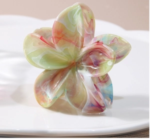 Détail d'une pince à cheveux fleur avec texture résine marbrée sur assiette blanche