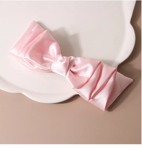 Dettaglio di un fiocco per capelli in raso rosa con trama di seta su piatto decorato