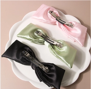 Dettaglio di fermagli per capelli a fiocco in raso rosa, verde e nero con clip a molla