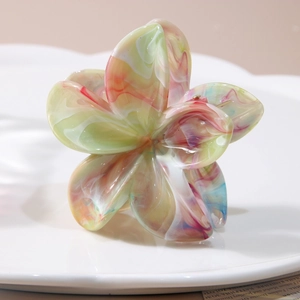 Pince à cheveux fleurie en résine marbrée colorée sur un plateau en porcelaine