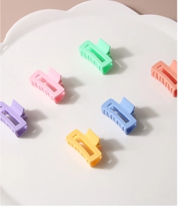Macro display of assorted matte candy color rectangular hair claws on a white tray