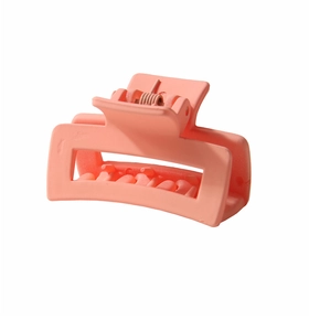 Detail of coral peach rectangular hair claw clip with matte finish and metal spring