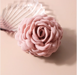 Macro detail of a 3D pink fabric rose hair claw clip with layered petals and soft texture