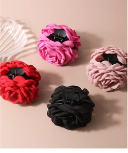 Detailed macro view showing four different colors of fabric rose flower hair claw clips