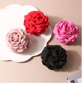 Detail of fabric rose hair claws showing multi-layered chiffon petals and textures