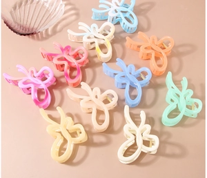Flat lay of colorful butterfly hair claws in pastel tones on a soft beige surface