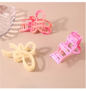 Macro detail of large wave butterfly hair claws in pink, orange and cream colors
