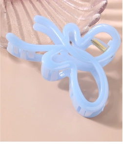 Detail of light blue butterfly hair claw clip with golden spring on decorative tray
