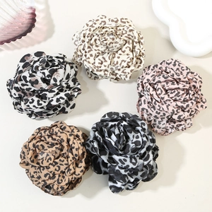 Detailed macro view of five chiffon rose hair clips in various leopard animal prints