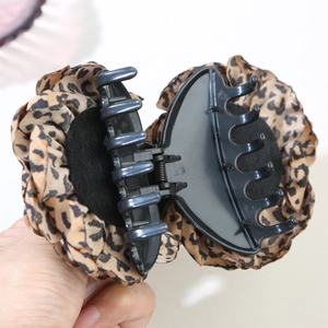 Detailed close-up of leopard print fabric claw clip with strong metal spring and teeth