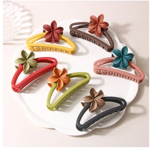 Detail view of large matte plumeria shark hair clips in six different vibrant colors