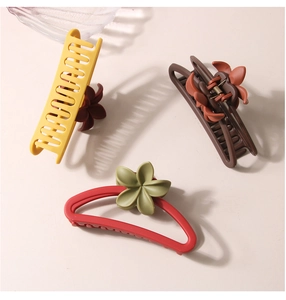 Detailed view of matte flower hair claws in yellow, brown, and red resin finishes