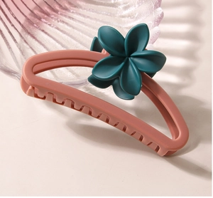 Detail of matte pink semi-circle hair claw clip with dark green plumeria flower