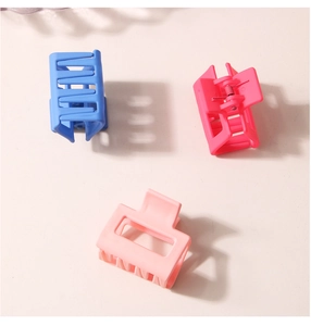 Gros plan de trois pinces à cheveux carrées mates de 4 cm en bleu marine, magenta et rose