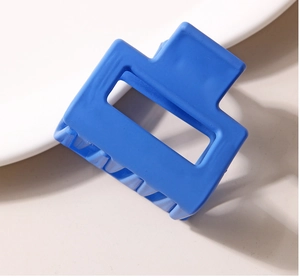 Gros plan d'une pince à cheveux carrée bleu mat de 4 cm au design géométrique