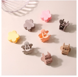 Detailed view of small matte flower hair claws in multiple soft macaron colors