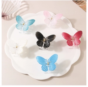 Detail of butterfly claw clips in various colors displayed on a white petal tray