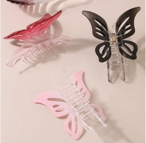 Détail de trois pinces à cheveux papillon dégradées en rose, noir et rose clair ajouré