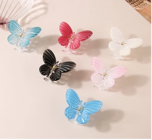 Detail view of 6 colorful butterfly hair claws in pastel tones on a cream background