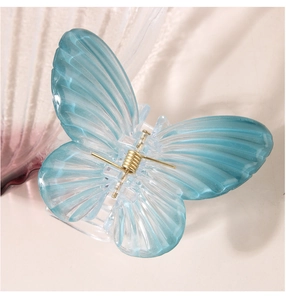Detailed close-up of light blue butterfly hair claw clip with golden metal spring