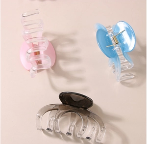 Close-up of pink, blue, and black resin claw clips with glossy finish and metal springs
