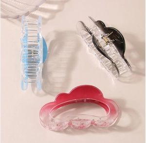 Three gradient cloud hair claws in light blue, grey and pink on a warm background
