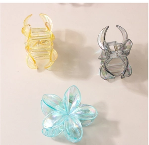 Détail de pinces à cheveux en forme de fleur irisées en jaune, gris et bleu ciel